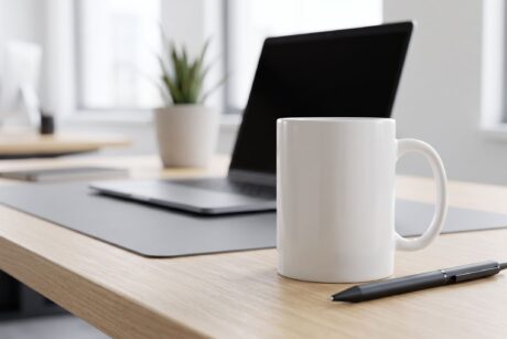 A branded coffee mug with a company logo sits on an office desk, a classic example of Promotional Products.